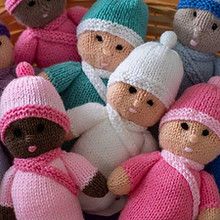 several knitted dolls sitting next to each other in front of a basket full of them