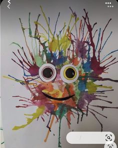 an art project with paint splattered on the wall and eyes painted in different colors