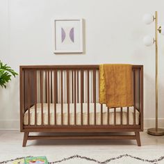 a baby crib in a white room with a yellow blanket on it's bed