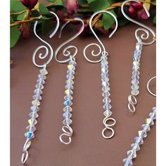 four pieces of glass beaded wire hanging from a branch with flowers in the background