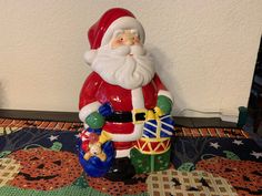 a santa clause figurine sitting on top of a rug next to a wall