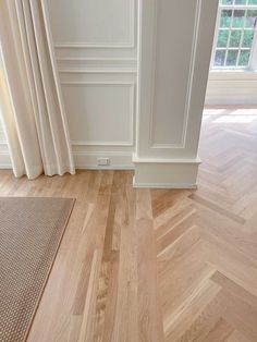 an empty room with white walls and wood floors, along with a rug on the floor