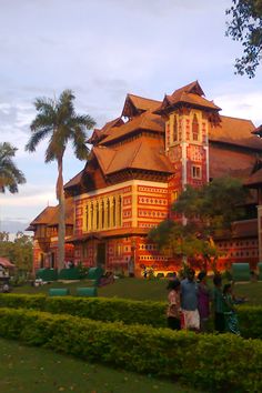 some people are standing in front of a large building with many windows and palm trees