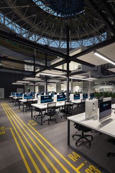 an office with multiple desks and computers in the middle of it's room