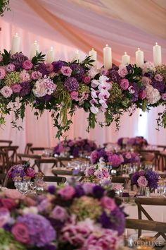 the tables are set with purple flowers and candles