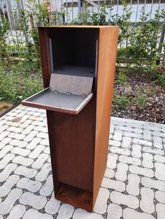 a wooden podium with an electronic device in it on a brick walkway next to a fence