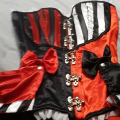 an orange and black corset is laying on a white sheet with silver buttons