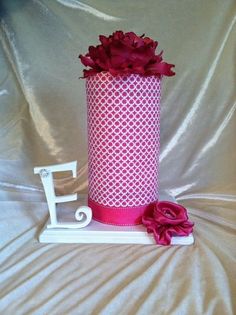 a pink and white vase with flowers in it on top of a table next to the letter j