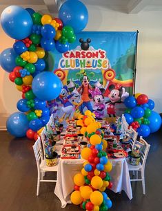 a mickey mouse themed birthday party with balloons and streamers on the ceiling, table