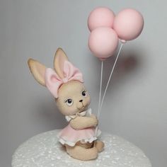 a small stuffed rabbit holding two pink balloons