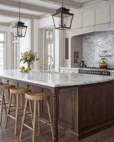 a large kitchen with marble counter tops and wooden stools in front of an island