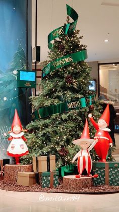 there is a christmas tree in the middle of this mall with elfs on it