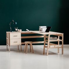 a desk with a laptop on top of it next to a chair and other items