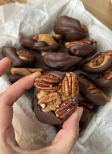 a person is holding some chocolate covered candies with pecans and walnuts on top