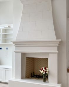 a white fireplace with some flowers in it