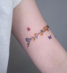 a woman's arm with colorful flowers and butterflies on the left side of her arm