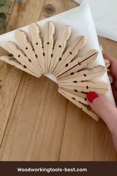 a hand holding a paper fan on top of a wooden table