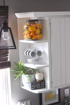 a kitchen with white cabinets and shelves filled with fruit