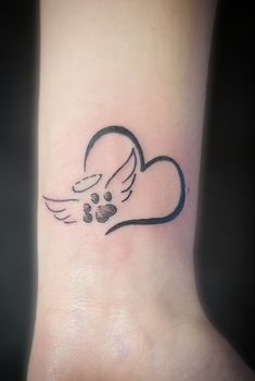 a dog paw and heart tattoo on the wrist with an angel's wing flying above it