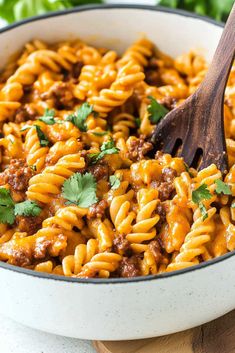 a skillet filled with pasta, meat and cilantro garnished with parsley