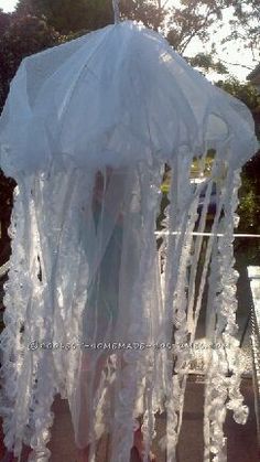 a woman is standing under an umbrella covered in white laces and plastic wrappers