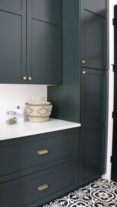 a kitchen with dark green cabinets and white counter tops