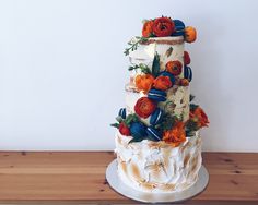 there is a multi layer cake with flowers on the top and bottom, sitting on a wooden table