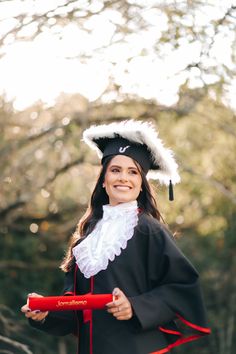 a woman wearing a graduation gown and holding a red object