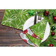 a place setting with green and red napkins, silverware and christmas tree decorations