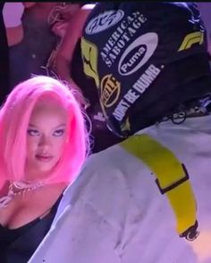 a woman with pink hair standing next to a motorcycle