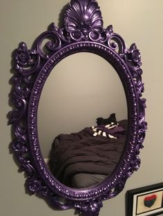 a purple mirror hanging on the wall above a bed