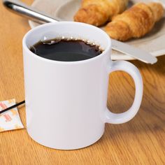 a cup of coffee next to some croissants on a plate with chopsticks