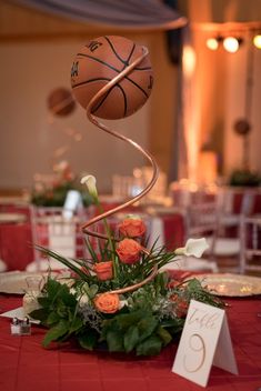 an arrangement of flowers and basketballs on a table at a wedding reception in the ballroom