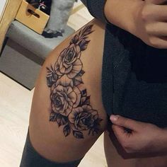 a woman is showing off her thigh with roses on the side and behind her leg