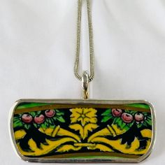 a yellow and green floral design on a silver plated chain necklace with a white background