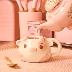 a teapot with a little pig face on it is being poured into the cup