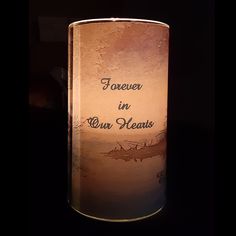 a candle that is lit up with the words forever in our hearts written on it