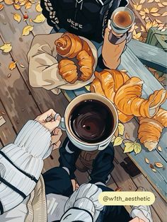 two people sitting at a table with coffee and croissants