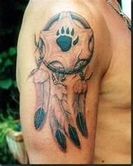 a man with a tattoo on his arm that has a bear's paw and dream catcher