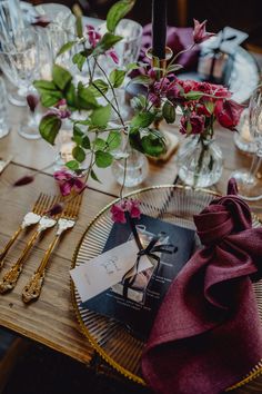 the table is set with flowers and goldware