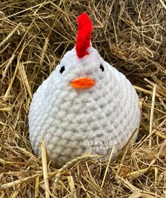 a crocheted chicken is sitting in the hay