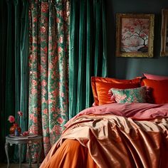 a bedroom with green curtains and orange bedding in front of a painting on the wall