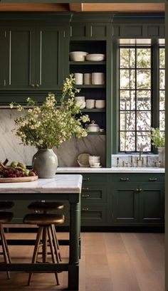 a kitchen with green cabinets and marble counter tops