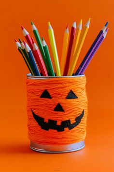 a cup filled with lots of colored pencils sitting on top of an orange surface