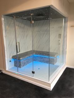 a glass enclosed shower with blue lights in the floor and seat on the back wall