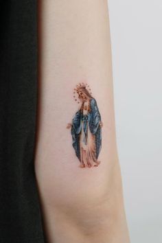 a woman's arm with a tattoo on it that has an image of the virgin mary