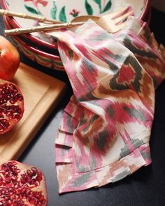 two pomegranates on a cutting board next to a bowl and knife