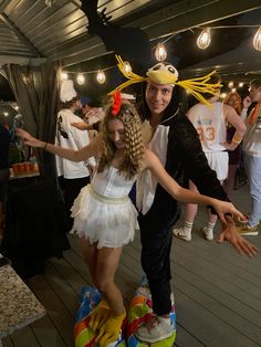 a man and woman in costume dancing on a wooden deck with other people standing around