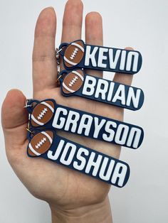 three keychains with footballs on them in the palm of a person's hand