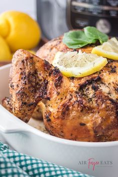 a close up of a chicken in a bowl with lemons